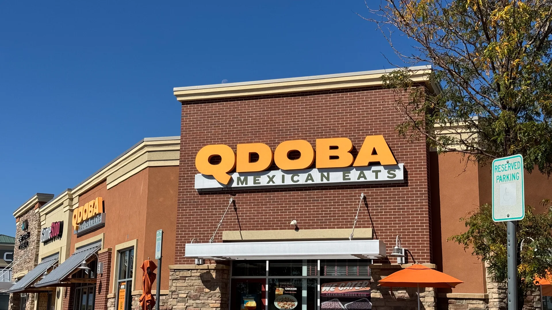 QDOBA Mexican Eats storefront with orange signage under a clear blue sky
