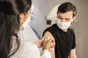 In this 2020 photograph, captured inside a clinical setting, a health care provider places a bandage on the injection site of a patient, who just received an influenza vaccine. The best way to prevent seasonal flu, is to get vaccinated every year. Centers for Disease Control and Prevention (CDC) recommends everyone 6-months of age and older get a flu vaccine every season.
